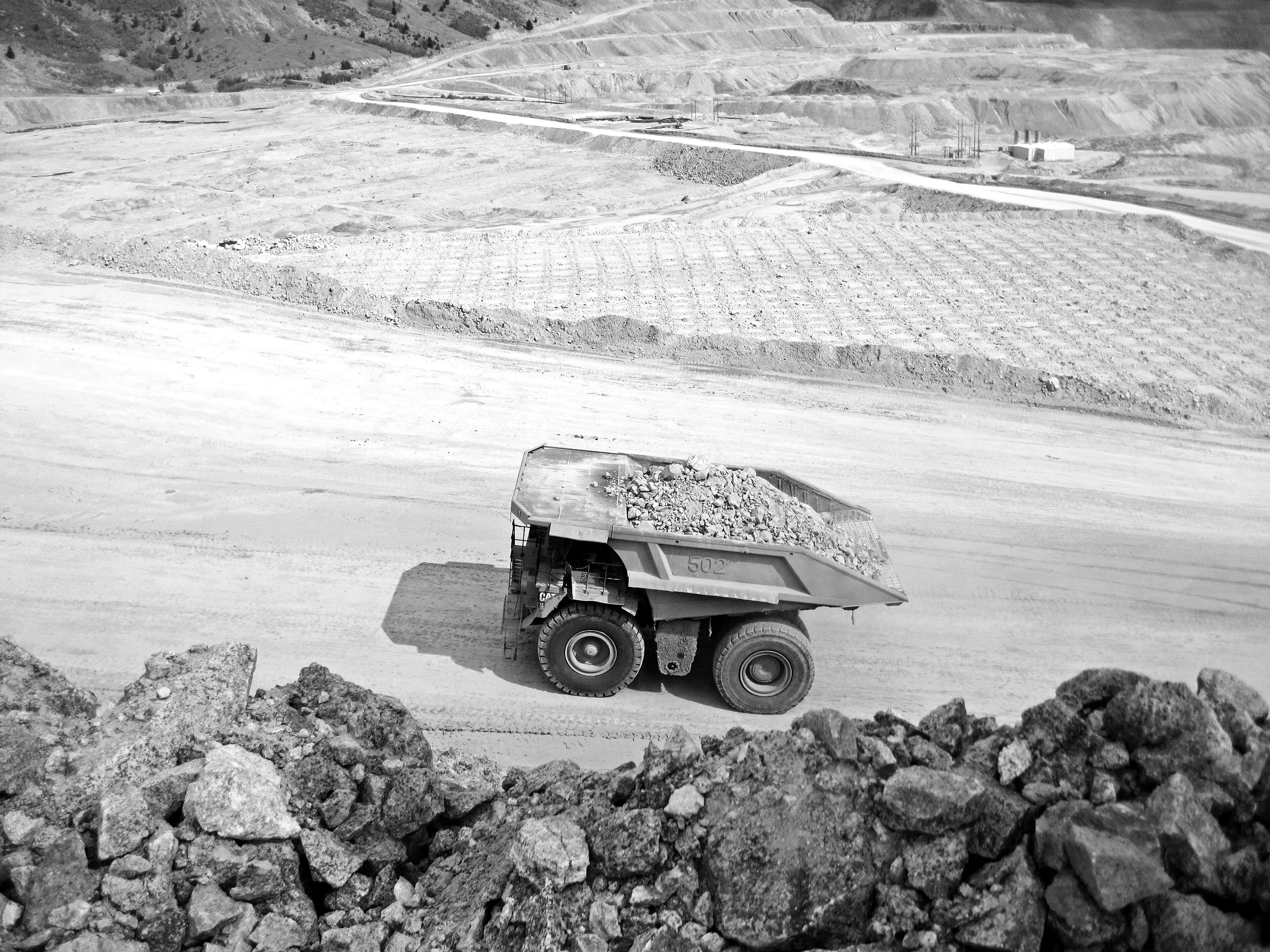 A haul truck loaded with broken rock on a mine bench.